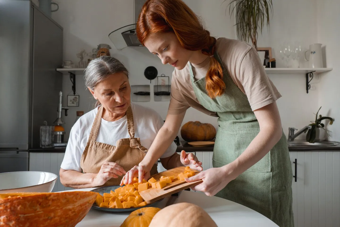An adult daughter and her mother preparing food together in a home kitchen
